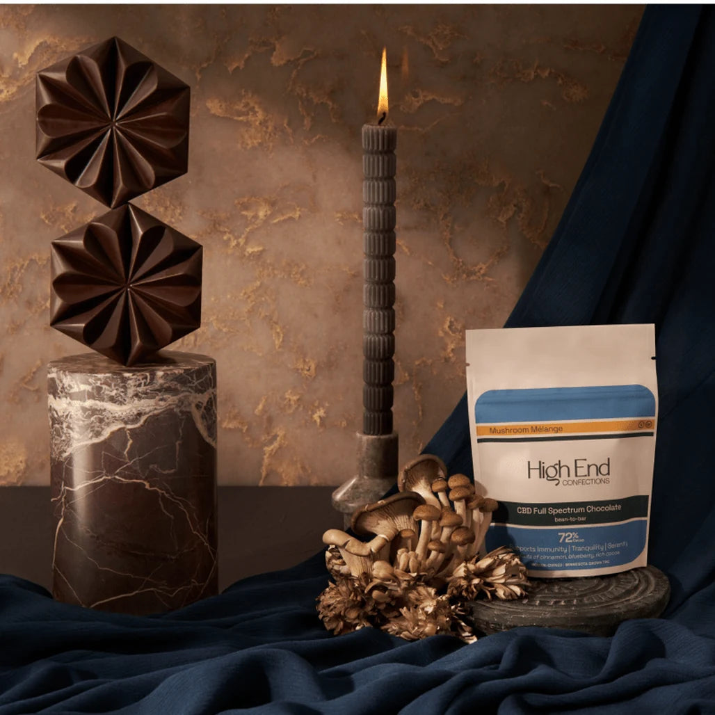 High End Confections Mushroom Mélange CBD Chocolate pouch with chocolate pieces, mushrooms and a candle
